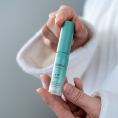 Hand holding a green eye serum bottle  of Plated Eye Serum with a blurred background lifestyle photo for size demonstration